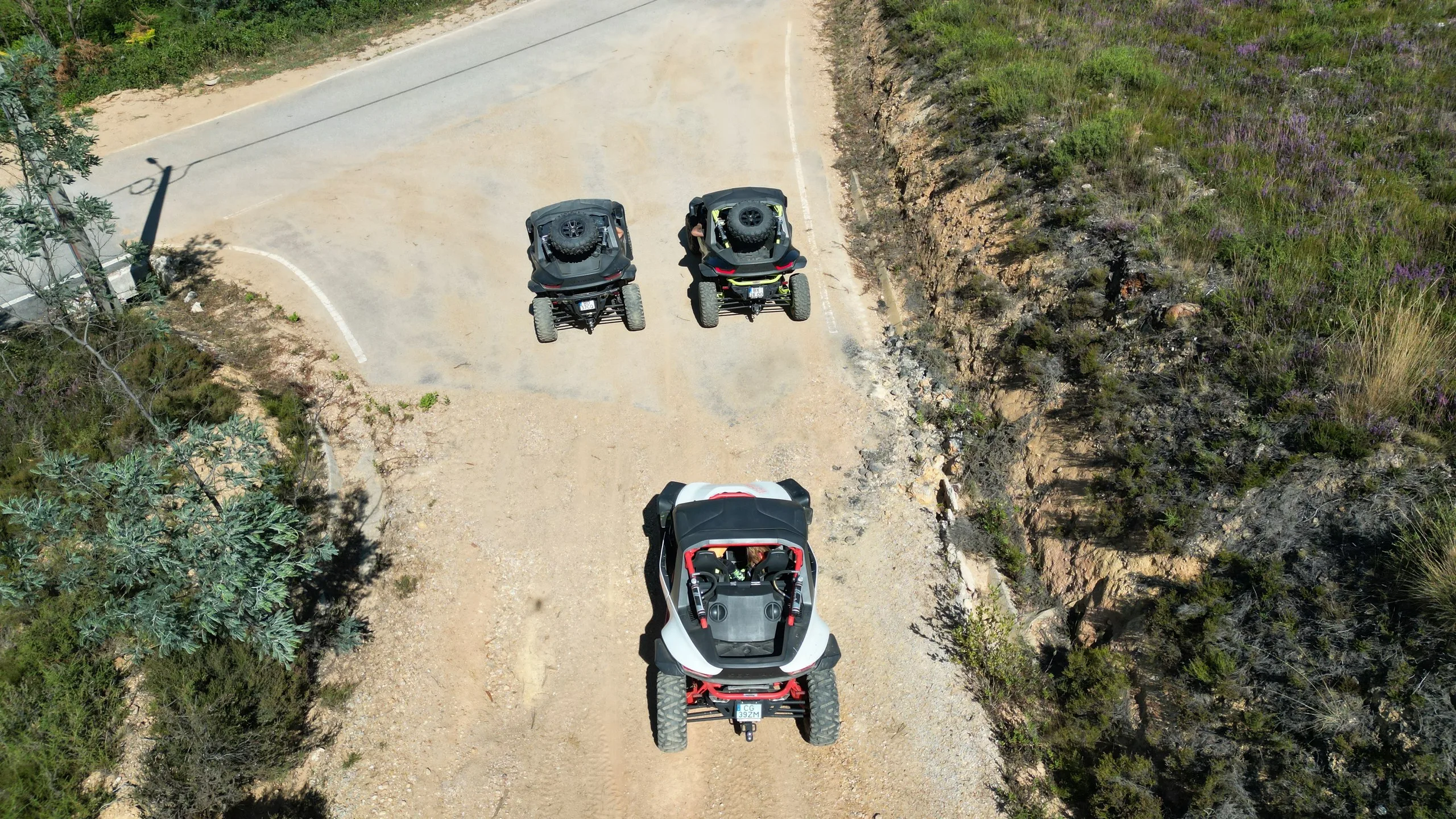 Vista aérea de três buggies numa estrada de terra batida rodeada de mato, durante um passeio off-road em Vila Nova de Poiares